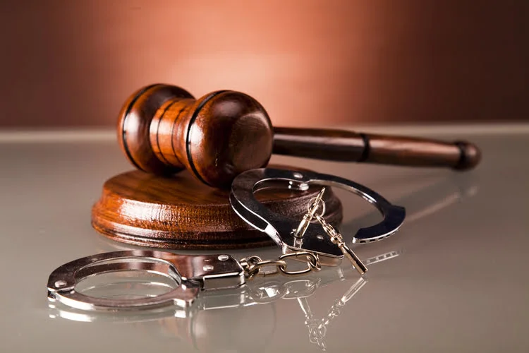 Man in handcuffs next to gavel